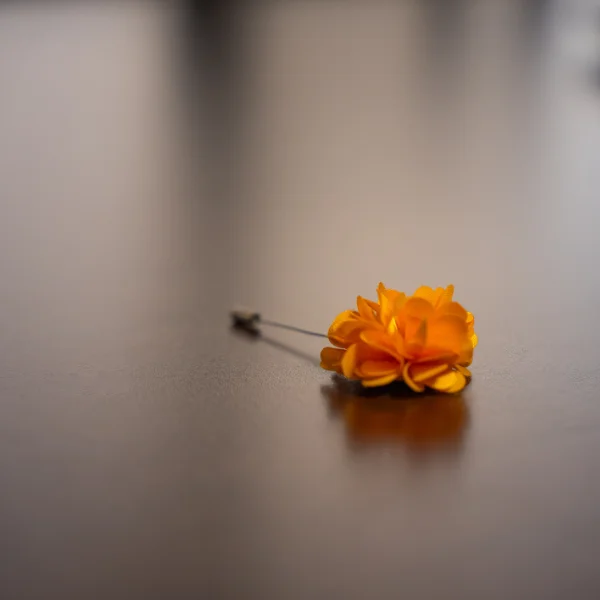 Photo of orange flower lapel pin on desk